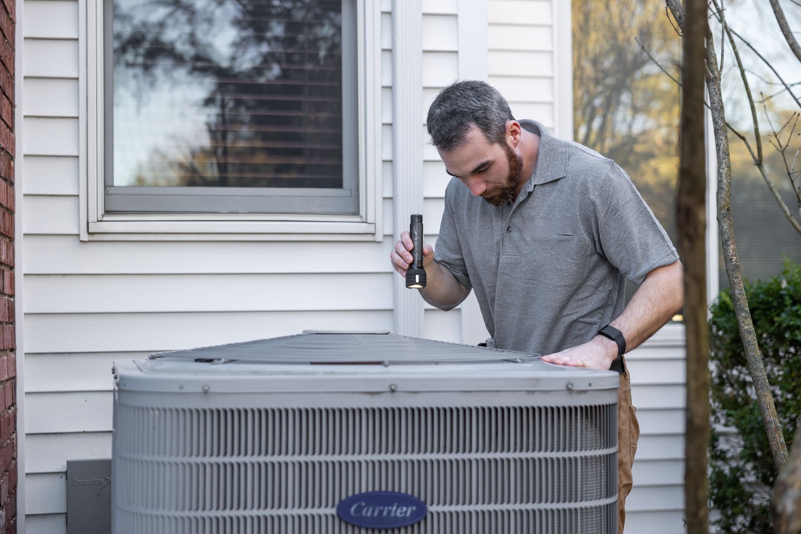 HVAC technician inspecting an outdoor air-conditioning unit